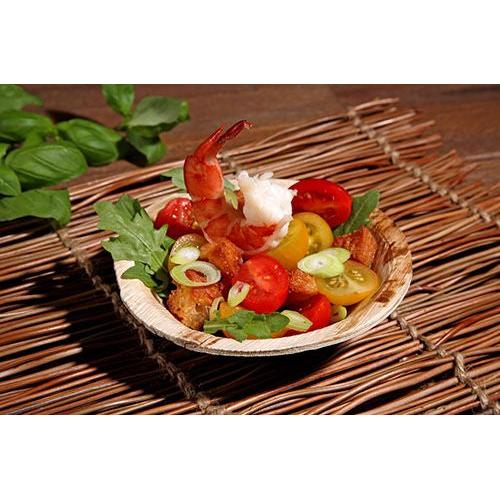 Genießen Sie Garnelen, Kirschtomaten, Croutons, Rucola und Frühlingszwiebeln in einer PAPSTAR GmbH Schale aus Palmblatt "pure" rund (13 cm), umweltfreundlich - perfektes nachhaltiges Einweggeschirr für umweltbewusste Veranstaltungen.