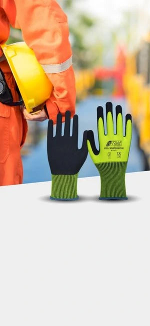 Arbeitsschutzhandschuhe in Schwarz und Grün mit Bauarbeiter in Schutzkleidung und Helm im Hintergrund.