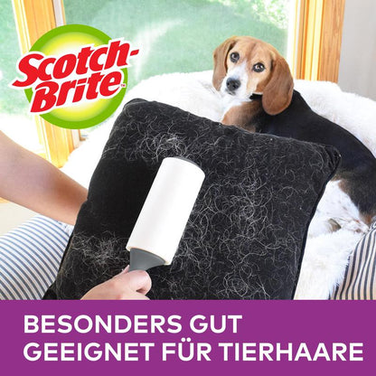 A person uses the Scotch-Brite™ Pet Extra Sticky* Roller for pet hair (48 sheets, 1 piece) by 3M Deutschland GmbH to remove pet hair from a black pillow. A dog lies on the couch; logo and "ESPECIALLY SUITABLE FOR PET HAIR" appear above.