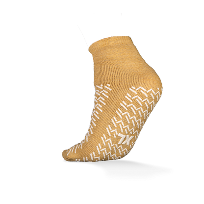 Abgebildet ist ein einzelner senfgelber ECO-PLUS Anti-Rutsch Einwegsocken beidseitig beschichtet von AMPri Handelsgesellschaft mbH auf weißem Hintergrund, mit weißen rutschfesten Griffen und ideal für medizinische Bereiche.