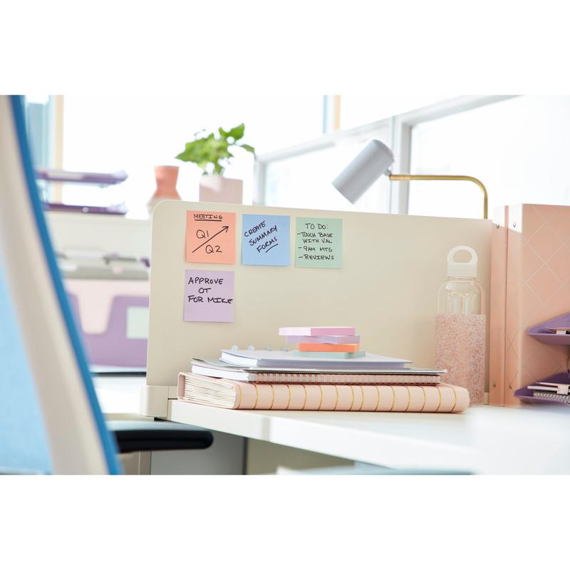 A tidy office workspace with Post-it® Super Sticky Notes (76 mm x 76 mm, 90 sheets/block, 100% PEFC) by 3M Deutschland GmbH on a partition, with notebooks, stacked papers, a glass water bottle, and organized folders in the background.