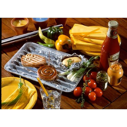 On a tabletop, 5 Starpak grill trays are presented, aluminum trays from Starpak with a burger patty, a cinnamon roll, a baked potato in foil, and sides like vegetables, sauces, plates, napkins, candles, and a drink - ideal for any barbecue party.