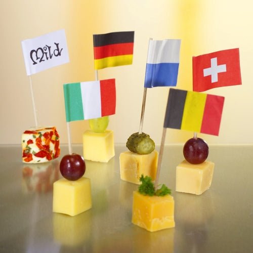 Five cheese cubes, each with a unique garnish and a different flag, are arranged on a high-quality and robust PAPSTAR 100 decoration pick from PAPSTAR GmbH on a reflective surface – ideal for stylish presentations at any international event.
