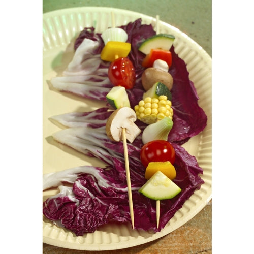 Two vegetable skewers made from PAPSTAR 1000 skewer sticks, bamboo “pure” from PAPSTAR GmbH with mushrooms, cherry tomatoes, corn, zucchini, onions, and peppers on a beige plate with purple radicchio leaves.