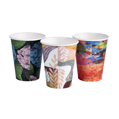 Three Art Series coffee mugs from Duni GmbH made of PAP/PLA with colorful designs - large flowers, leaves, abstract patterns, or a colorful paint look. Each mug is environmentally friendly and biodegradable.