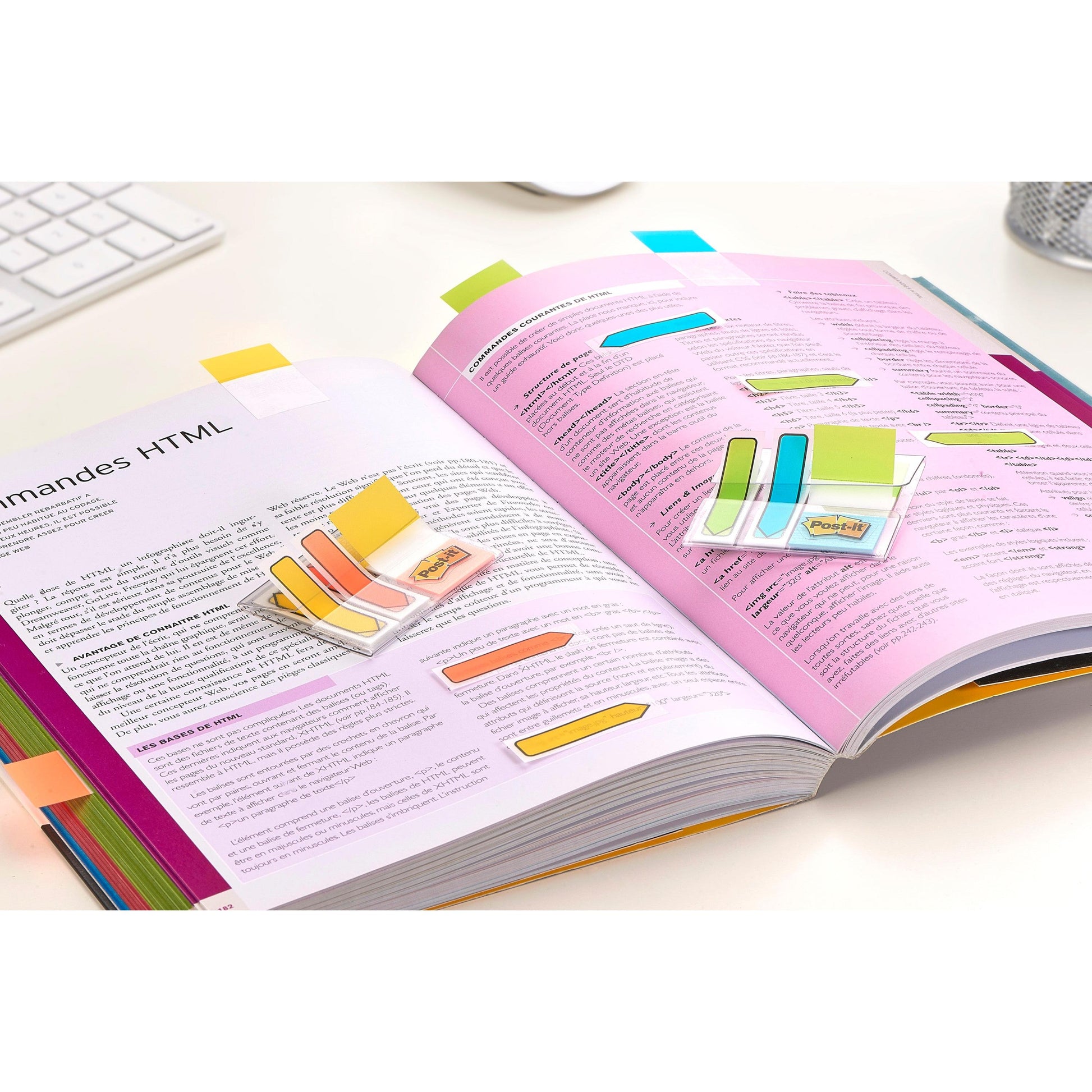 Ein aufgeschlagenes Schulbuch ist mit Post-it® Index Strong Ablagetabs, Mini (Blau, Violett, Rosa und Gelb, 15,8 x 38,1 mm), 40 Haftstreifen/Spender von 3M Deutschland GmbH gekennzeichnet. Im Hintergrund sind teilweise eine Tastatur und ein Stifthalter zu sehen.