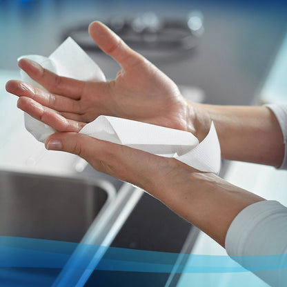 A person uses a white Scott® Hand Towels - MultiFold paper towel (Kimberly-Clark GmbH, 16 Clips x 250 Sheets) over a sink in a modern kitchen for hygienic hand drying.