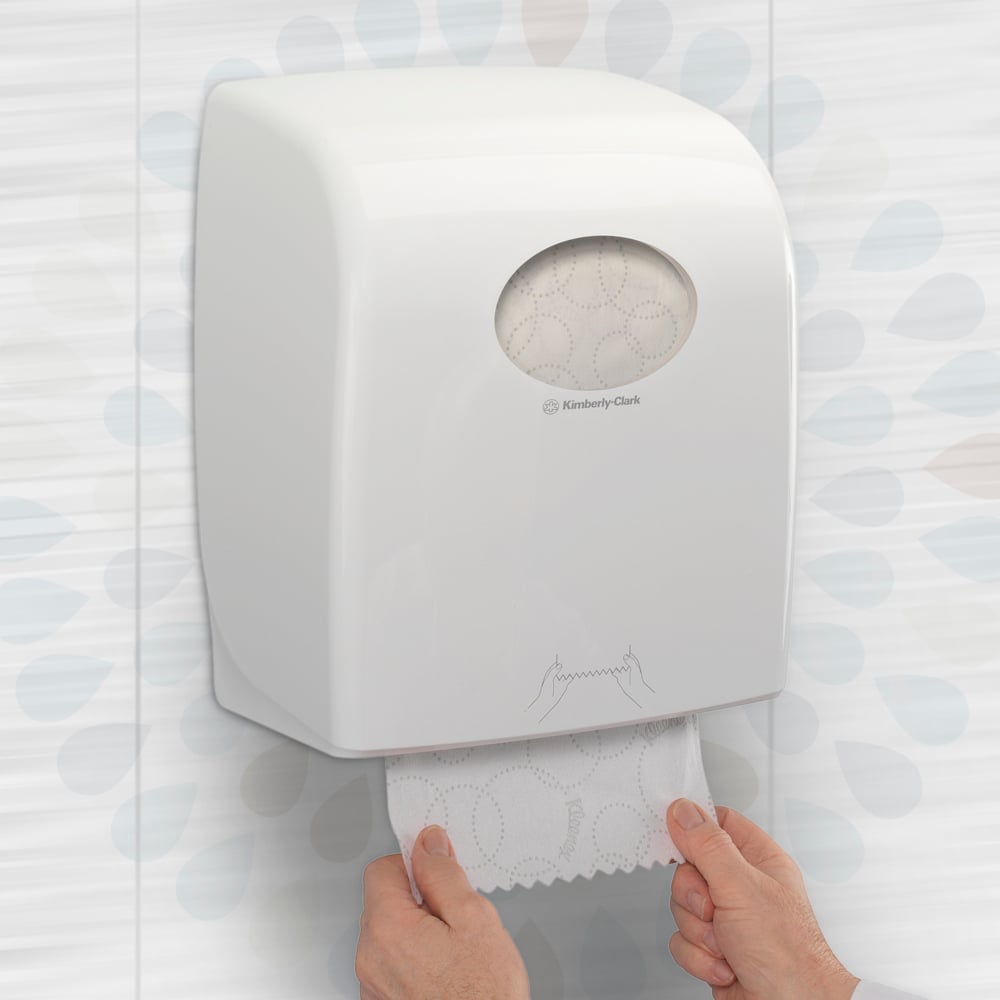 Eine Person zieht eine Kleenex® ULTRA™ Handtücher-Rolle (Weiß, 150m) von Kimberly-Clark GmbH aus einem Wandspender in einer Toilette und sorgt so für hygienische Handtrocknung. Verpackung: 6 Rollen/Karton.
