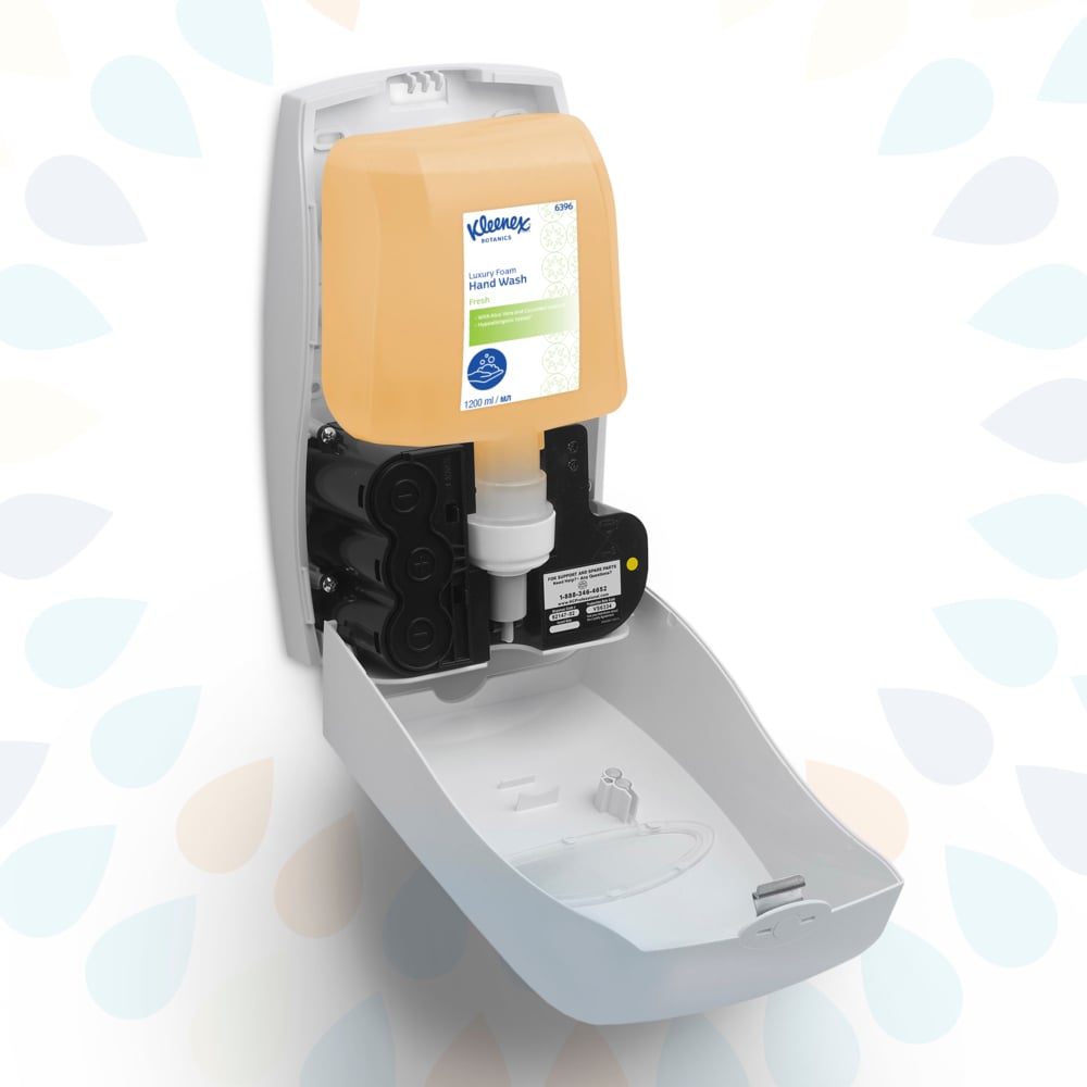 A white wall-mounted dispenser is seen with the front open, revealing a 1.2L Kleenex® Botanics™ Luxury Foam Hand Wash cassette from Kimberly-Clark GmbH; the transparent beige cartridge fits perfectly inside.