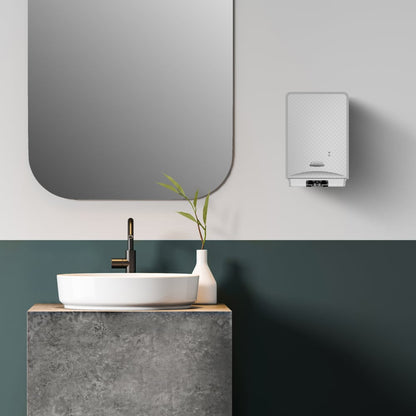 A modern bathroom with a round white sink on a concrete countertop, a black faucet, a white vase with green stems, a large rectangular mirror, and a wall-mounted Kimberly-Clark Kleenex® Botanics™ Luxury Foam Hand Wash 1.2L cassette.