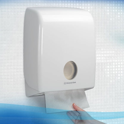 A hand pulls a Scott® EXCELLENT Interfold Hand Towel (Kimberly-Clark GmbH) from a wall-mounted white dispenser, ensuring hygienic hand drying in front of a tiled wall.