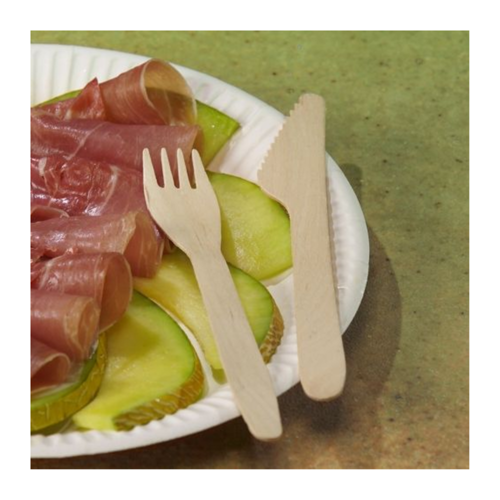 A white paper plate with green apple slices and prosciutto, next to PAPSTAR wooden forks "pure" 16.5 cm - eco-friendly and sturdy (100 pieces) - from PAPSTAR GmbH, along with a wooden knife, on a green background.