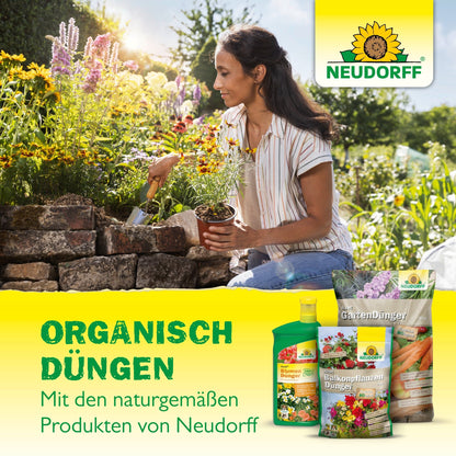 A woman kneels in the garden and tends to the flowers with a trowel. Bags and bottles of Neudorff Shop Azet Perennial Fertilizer can be seen, indicating the organic fertilization of perennials with the natural product from Neudorff Shop.