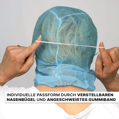 Eine Person setzt sich einen blauen ARNOMED COVER PP-ASTROHAUBE MIT 2-LAGIGEM MUNDSCHUTZ der ARNOWA GmbH mit einem Gummiband auf den Kopf, der mit einem verstellbaren Nasenclip versehen ist. Ein deutscher Text, der die Eigenschaften hervorhebt, erscheint am unteren Rand.