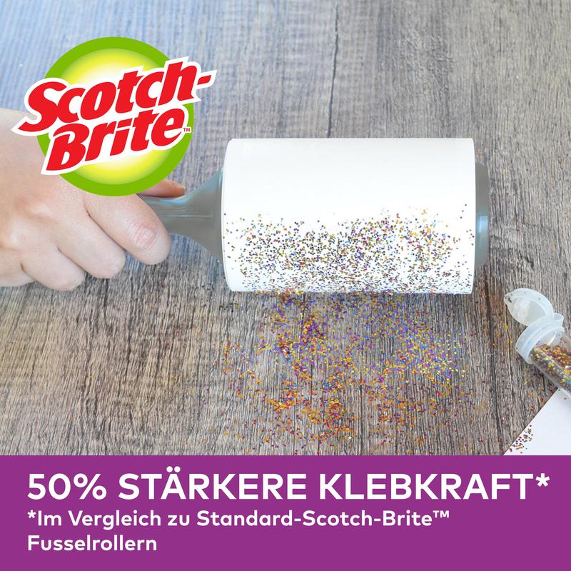 A hand uses the Scotch-Brite™ Pet Extra Sticky* Roller for pet hair by 3M Deutschland GmbH (48 sheets) to remove spilled glitter from a wooden surface. German advertisement: 50% stronger adhesion than standard models.