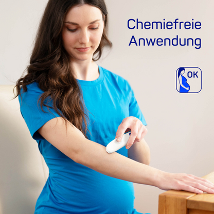 A pregnant woman in a blue shirt uses the HARTMANN insect bite healer | Pack (1 piece) by Paul Hartmann AG on her arm, with the text "chemical-free application" and a logo as a release signal. She stands in a softly lit room.