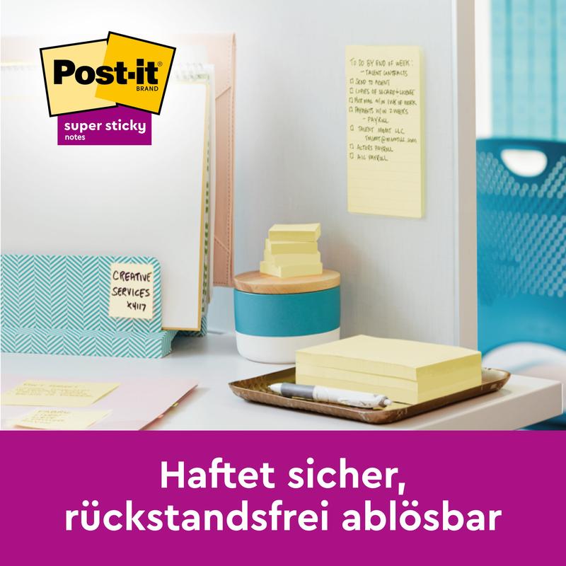 A workspace with Post-it® Super Sticky Notes, 76 mm x 76 mm, 90 sheets/block from 3M Deutschland GmbH on the desk and wall with notebooks, pen, and folders. Lower text in German: "Sticks securely, removes cleanly."