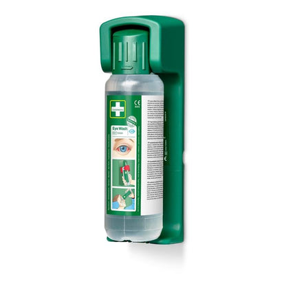 A green Orkla Wound Care AB wall mount contains a 500 ml eye wash bottle with a green cap, the inscription "Eye Wash" and usage instructions; including a glow-in-the-dark sign. The package contains 1 wall mount for emergency eye wash stations.