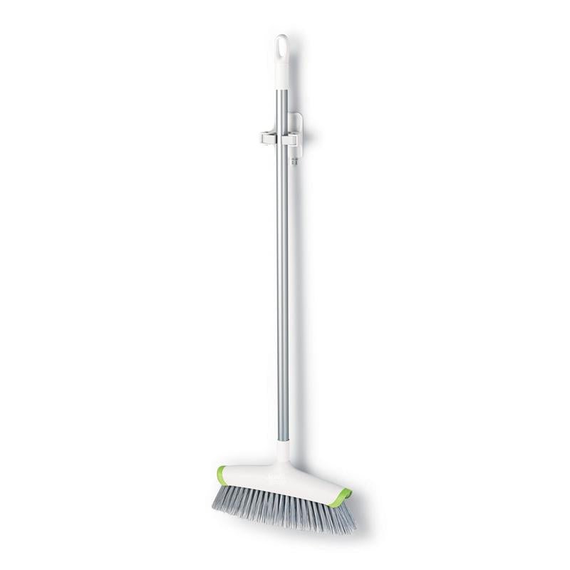 A white-silver broom with gray bristles and green corners hangs vertically on a 3M Deutschland GmbH Command™ broom holder, 17007-FR, a wall-mounted cleaning tool holder, against a plain white background.