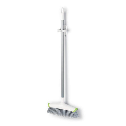 A white-silver broom with gray bristles and green corners hangs vertically on a 3M Deutschland GmbH Command™ broom holder, 17007-FR, a wall-mounted cleaning tool holder, against a plain white background.