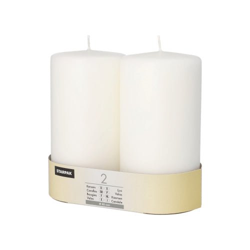 Two large, white Starpak pillar candles (Ø 80 mm) with flat top and unlit wick stand side by side in a beige and white Starpak packaging.