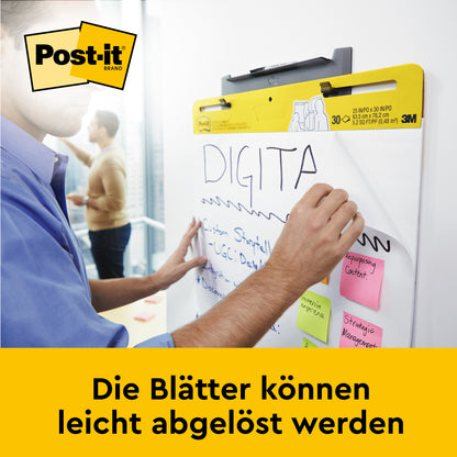 Jemand schreibt auf dem Post-it® Super Sticky selbsthaftenden Meeting Chart/Flipchart für Wand-Montage 559 (63,5 x 76,2 cm) von 3M Deutschland GmbH. Mehrere Haftnotizen kleben darauf. Die Blätter lassen sich leicht ablösen.