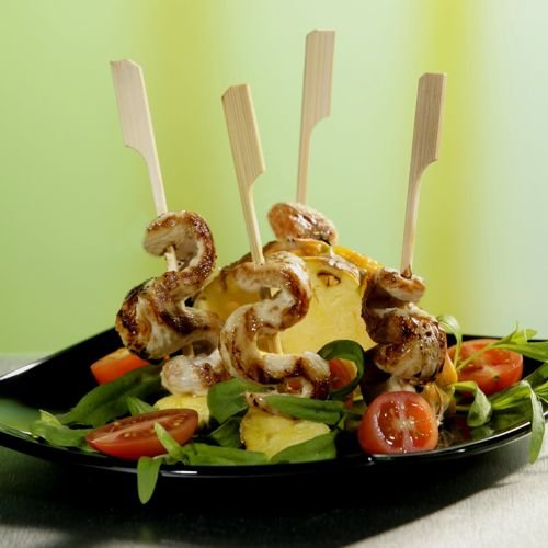PAPSTAR "Golf" 21 cm Skewers by PAPSTAR GmbH: Perfect BBQ and grill party skewers made with chicken and pineapple on fresh salads with cherry tomatoes, served on a black plate against a green-and-yellow background. 250 pieces in a cardboard tray.
