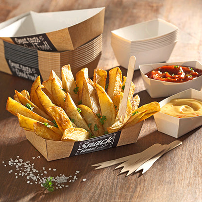 Potato wedges are served in PAPSTAR 50 French fries trays "pure" (3.5 x 7 cm) from PAPSTAR GmbH, garnished with parsley, next to wooden forks, sea salt, and two square bowls with salsa and yellow dip on a wooden table.