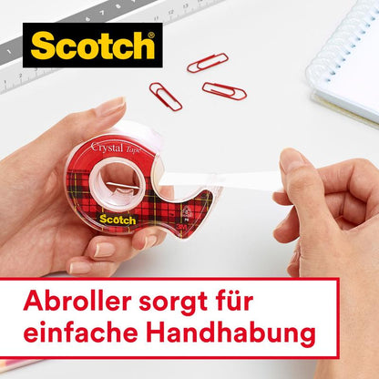 A person pulls Scotch® Crystal Tape (19mm x 25m + 5m FREE) from 3M out of a red hand dispenser. In the image are red paperclips, a ruler, and a notepad. The text: "Dispenser ensures easy handling.