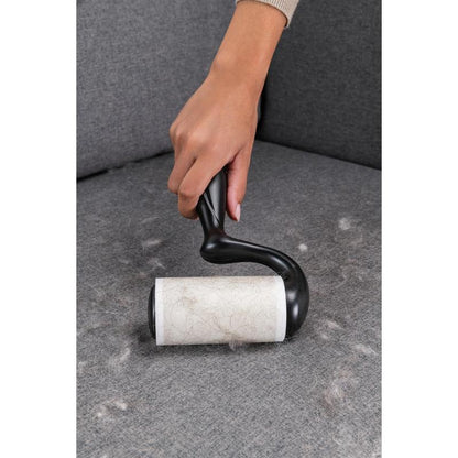 A hand uses the Scotch-Brite™ Everyday Clean Lint Roller for flat surfaces, 56 sheets (3M Deutschland GmbH), to remove pet hair from a gray couch and keep surfaces clean.