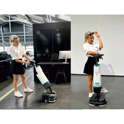 Zwei Frauen in weißen Hemden und schwarzen Röcken benutzen die Arcora International GmbH Tiger 40 Bodenreinigungsmaschine | Karton (1 Stück) in Innenräumen; eine bedient die Maschine, während die andere lächelnd ihre professionelle Reinigung präsentiert.