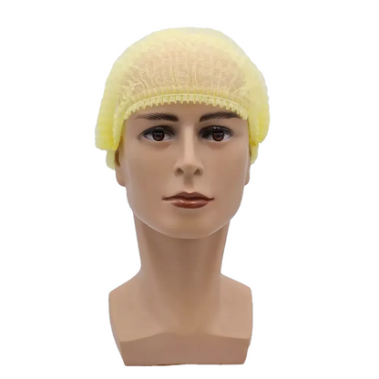 A mannequin head presents a yellow AMPri MED-COMFORT clip cap 52 cm, made of polypropylene by AMPri Handelsgesellschaft mbH, with a neutral expression against a plain white background, emphasizing hygienic protection.