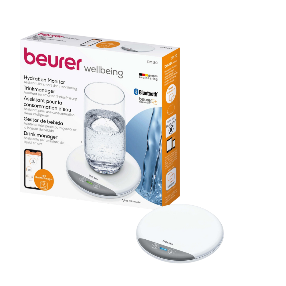 The image shows a Beurer DM 20 Drink Manager Hydration Monitor in its packaging. The box presents the product next to a glass of water and emphasizes its Bluetooth connectivity. The device is a small, white round pad with two touch-sensitive buttons and can be easily integrated with the beurer HealthManager Pro.