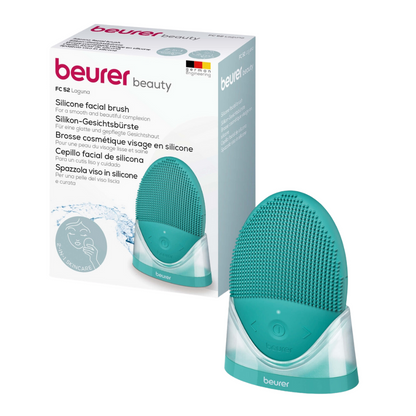Image of the Beurer FC 52 Laguna Silicone Facial Brush (Package: 1 piece) from Beurer GmbH and its packaging. The turquoise, oval facial brush rests on a white charging station and ensures deep pore cleansing through vibration technology. The packaging shows text in several languages and an image of a woman's cleansed face.