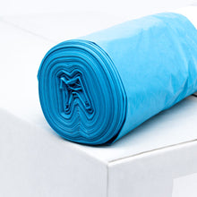 Eine Rolle blauer DEISS LDPE Müllsack Typ 60, 20772, 70 Liter von EMIL DEISS KG (GmbH + Co.) liegt auf einer weißen Kiste. Diese langlebigen Säcke, bekannt für ihre Reißfestigkeit, sind ordentlich gerollt, um die Schichtstruktur des Recyclingmaterials sichtbar zu machen. Der Hintergrund bleibt schlicht und minimalistisch.