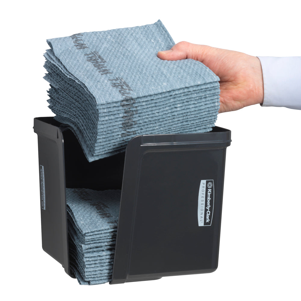 Eine Hand legt viertelgefaltete Wischtücher in den grauen Kimberly-Clark Professional™ Wischtuch-Spender von Kimberly-Clark GmbH ein - für hygienische Tuchentnahme. Die ordentlich gefalteten Tücher und das vordere Etikett sind sichtbar.