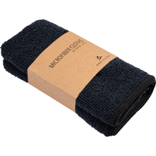 A set of two black ENA Living microfiber cloths (30x30 cm) from Abena Re-Seller GmbH, each folded with a brown label with the inscription "Microfiber Cloths 30 x 30 cm" and a minimalist logo - ideal for use as cleaning cloths in the household.