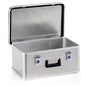 The Novocal transport box is a rectangular, stackable aluminum box with a hinged lid, blue and silver toggle latch, textured surface, black handle, and an open lid revealing the empty interior.