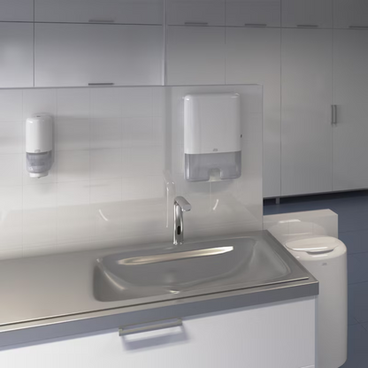Ein modernes Waschbecken mit Edelstahlplatte und Wasserhahn ist ein Highlight des Elevation Designs. An der gefliesten Wand über dem Waschbecken sind ein Seifenspender und ein Papierhandtuchspender angebracht, während im Hintergrund ein Tork 563000 Abfallbehälter Elevation 50 Liter B1 von TORK – Essity Professional Hygiene Germany GmbH zu sehen ist.