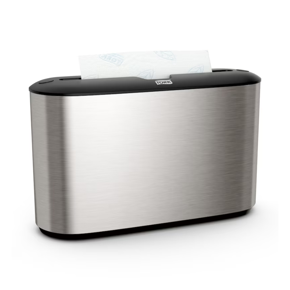 The Tork Xpress® 460005 table dispenser for multifold towels from Essity Professional Hygiene Germany GmbH is characterized by an elegant stainless steel design. Its silver metallic exterior is accented by a black top, with a section of white paper towels elegantly protruding from the top slot. Ideal for users of multifold towels who appreciate both style and functionality.