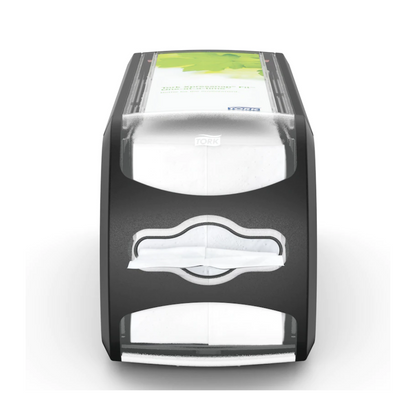 Pictured is the napkin dispenser Tork Xpressnap Fit® 272901 from Essity Professional Hygiene Germany GmbH. This black-gray dispenser has a transparent front containing white napkins and a green advertising space on the top. The 'Tork' logo is visible and highlights the efficient single napkin dispensing system of the Tork Xpressnap Fit.