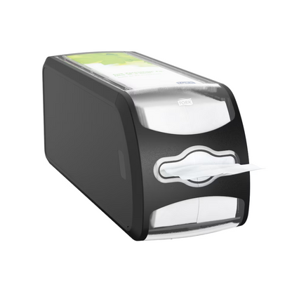 The table napkin dispenser Tork Xpressnap Fit® 272901 from TORK - Essity Professional Hygiene Germany GmbH is a black-silver rectangular dispenser that presents a single, partially dispensed napkin. The top features a transparent section showing a green-white design or label.