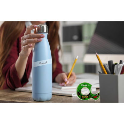 Eine Person sitzt an einem Schreibtisch mit einer hellblauen "Hannah"-Wasserflasche. Auf dem Schreibtisch liegen ein Notizbuch, Bleistifte, Stifte in einem Becher und das Scotch® Magic™ Unsichtbares Klebeband (19 mm x 25 mm) mit Spender (+5 m gratis) von 3M Deutschland GmbH. Dahinter befinden sich Ablagen und Mappen.