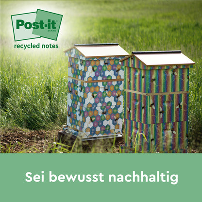 Zwei bunte Bienenstöcke mit sechseckigen Mustern stehen auf einer Wiese im Sonnenlicht. In der Ecke erscheint das Logo von Post-it® Super Sticky 100 % Recycling Notes by 3M Deutschland GmbH. Der Text darunter lautet: "Sei bewusst nachhaltig.
