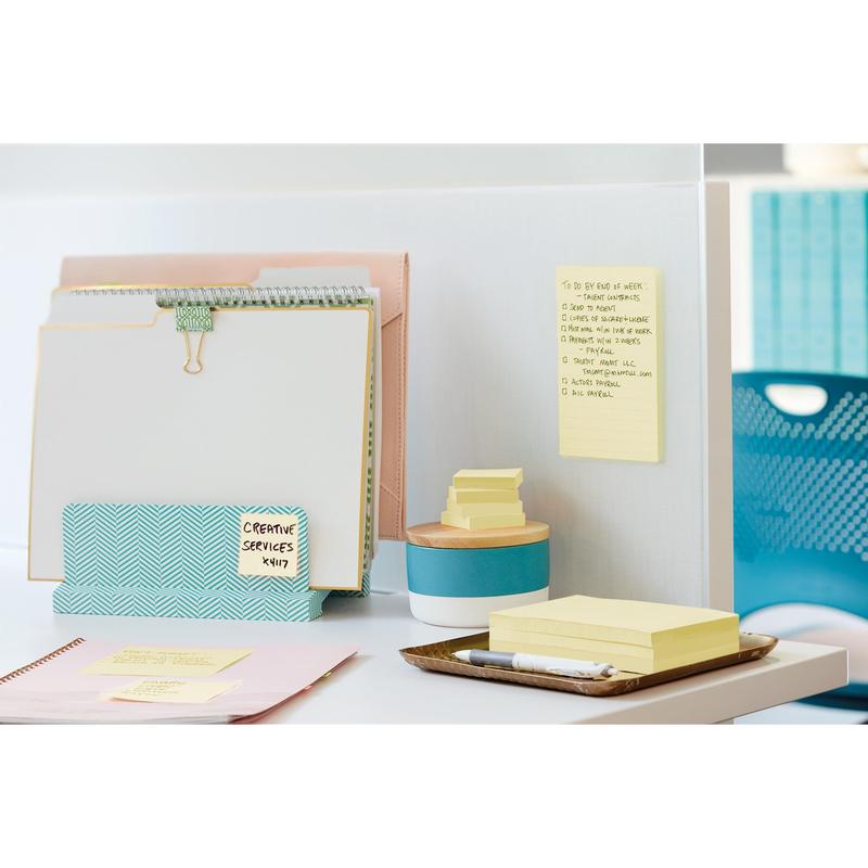 On a white desk are 3M Post-it® Super Sticky Notes (76 mm x 127 mm, 90 sheets/block, 100% PEFC) from 3M Deutschland GmbH, attached to a partition and stacked next to a blue container, alongside binders and office supplies.