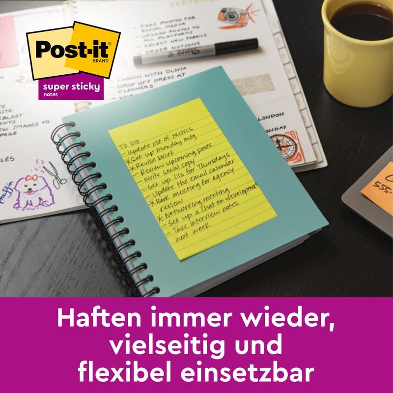 Tá Post-it® Super Sticky Note buí ó 3M Deutschland GmbH, Formáid Mhór (45 Bileog), suite ar dheasc le páipéir, caife agus stáiseanóireacht; tá lógó Post-it suite sa chúinne uachtarach ar chlé agus tá an téacs Gearmáinis le feiceáil ag bun an íomhá.